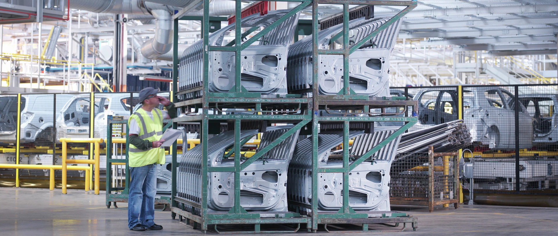 Worker inspecting stacked automotive body panels in DP World logistics facility