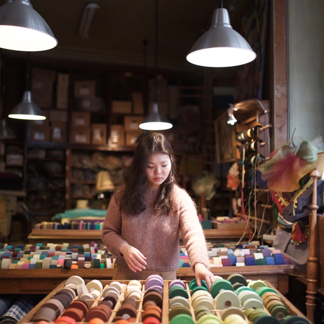 Worker sorting ribbon spools in a textile workshop