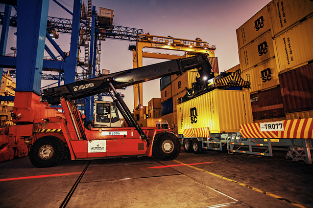 Container stripping at Dar es Salaam terminal with reach stacker lifting shipping container in yard