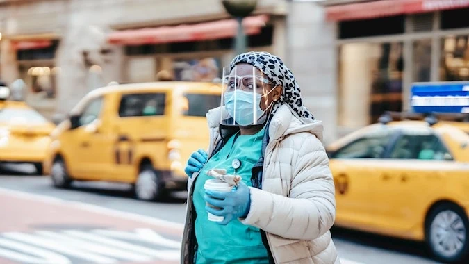 Healthcare worker assisting a patient with mobility support in a city setting